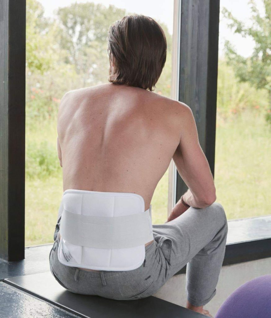 Man with his bare back to the viewer, wearing a MagnetBandage on his lower back