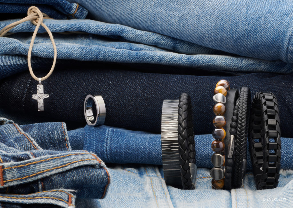 Selection of men's magnetic bracelets in front of a pile of denim clothes. From ENERGETIX and Gaia Magnets