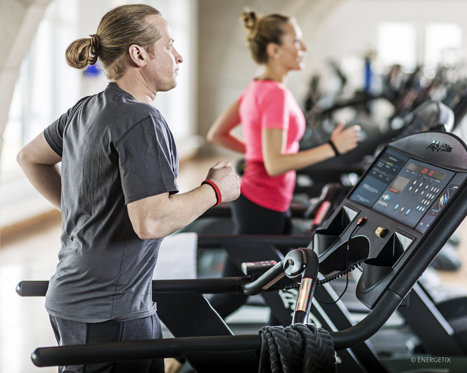 A couple of people next to each other running on treadmills, wearing ENERGETIX SportEX Magnetic Bracelets