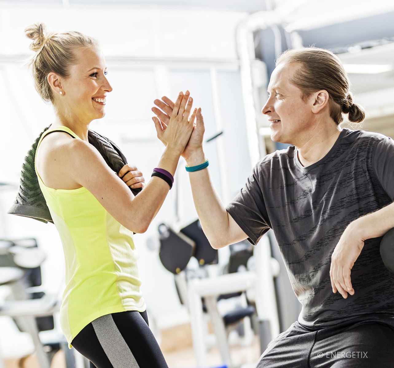 Two people in the gym high-fiving each other, both wearing ENERGETIX sportEX Magnetic Bracelets