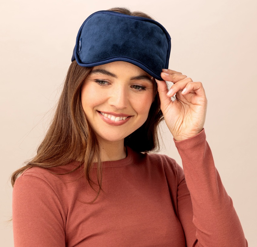 A smiling model wearing a Magnet Relax face mask on her forehead