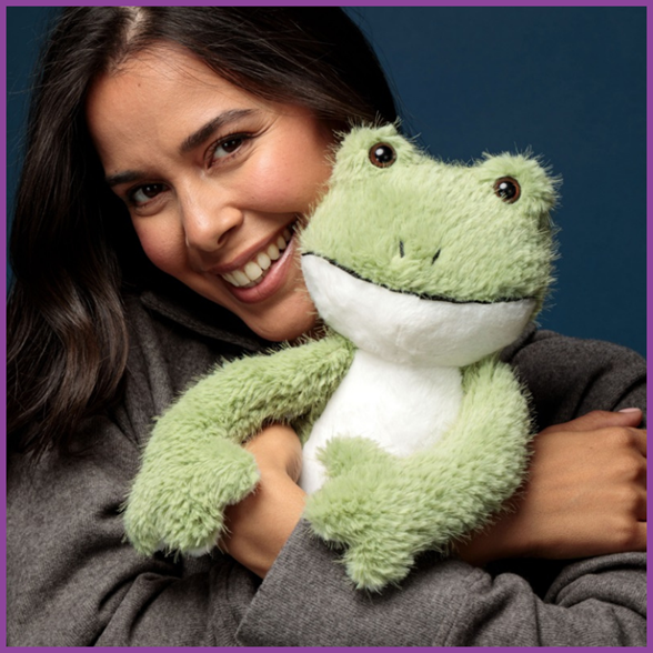 A model cuddling Paul Power, the plush toy frog with magnets.