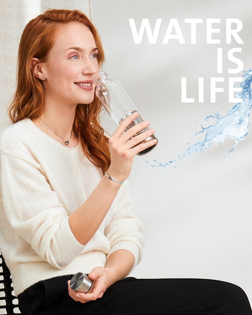 A model drinking from an ENERGETIX BalancePlus bottle, with text that reads 'Water is life'