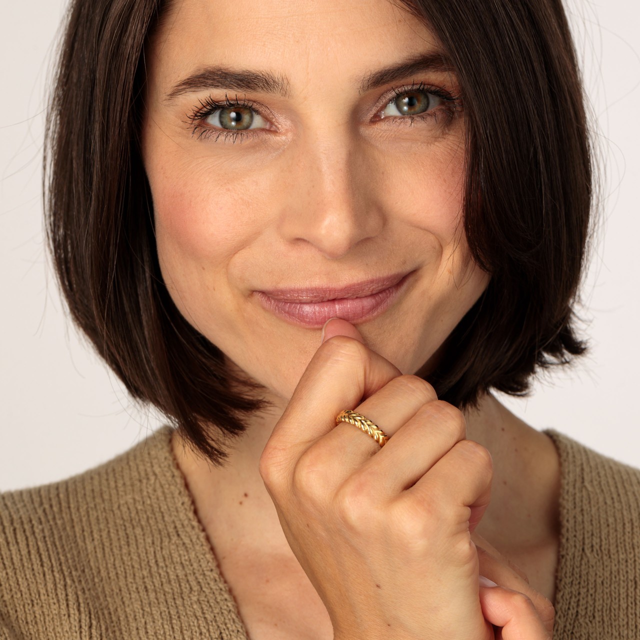 Gold-coloured heart ring A smiling model wearing a Gold-coloured heart ring