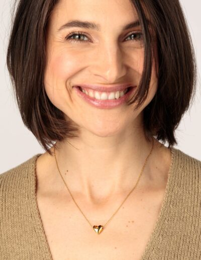 Smiling model wearing a Gold-coloured necklace with rounded heart pendant