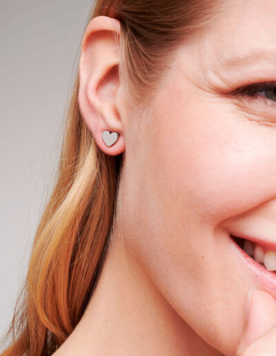 Model wearing simple and cute, silver colour heart shaped ear studs