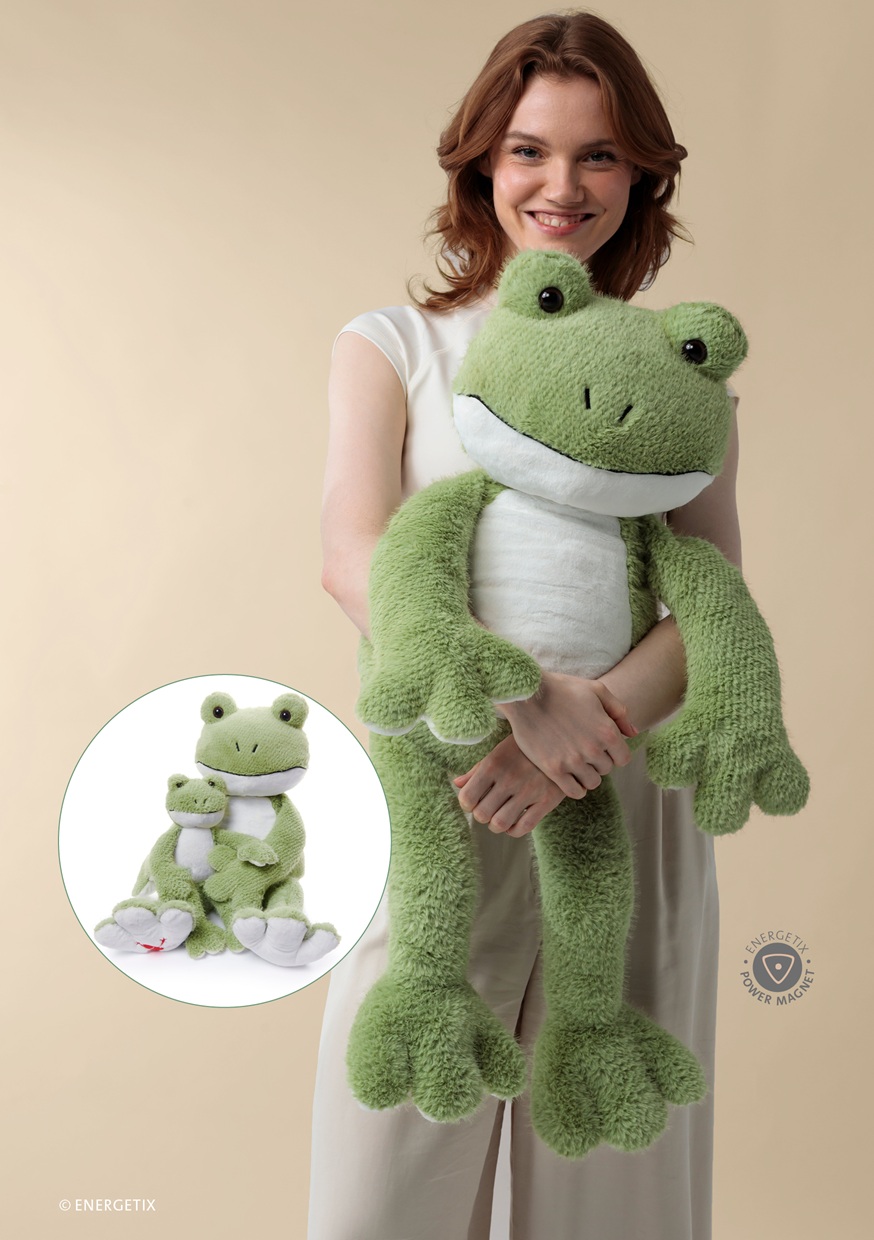 A woman holding a Paul Power plush toy frog - the XL collectors edition. A circle next to her shows the XL frog with the regular size cuddly toy. Both with integrated magnets