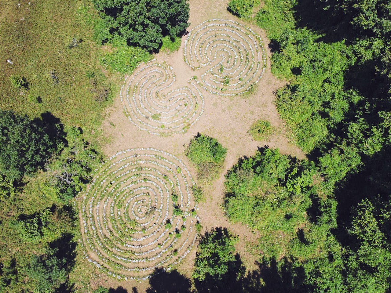An arial photo showing three different size walking meditation walking meditation walking meditation labyrinths near trees.