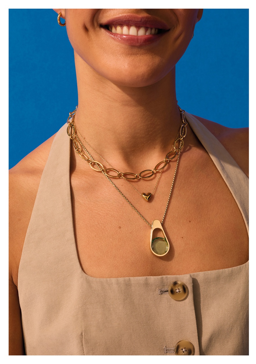 A model's neck, wearing a selection of ENERGETIX gold coloured necklaces.